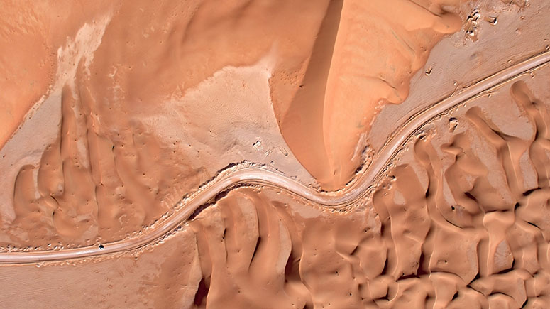 Aerial view of road through desert dunes